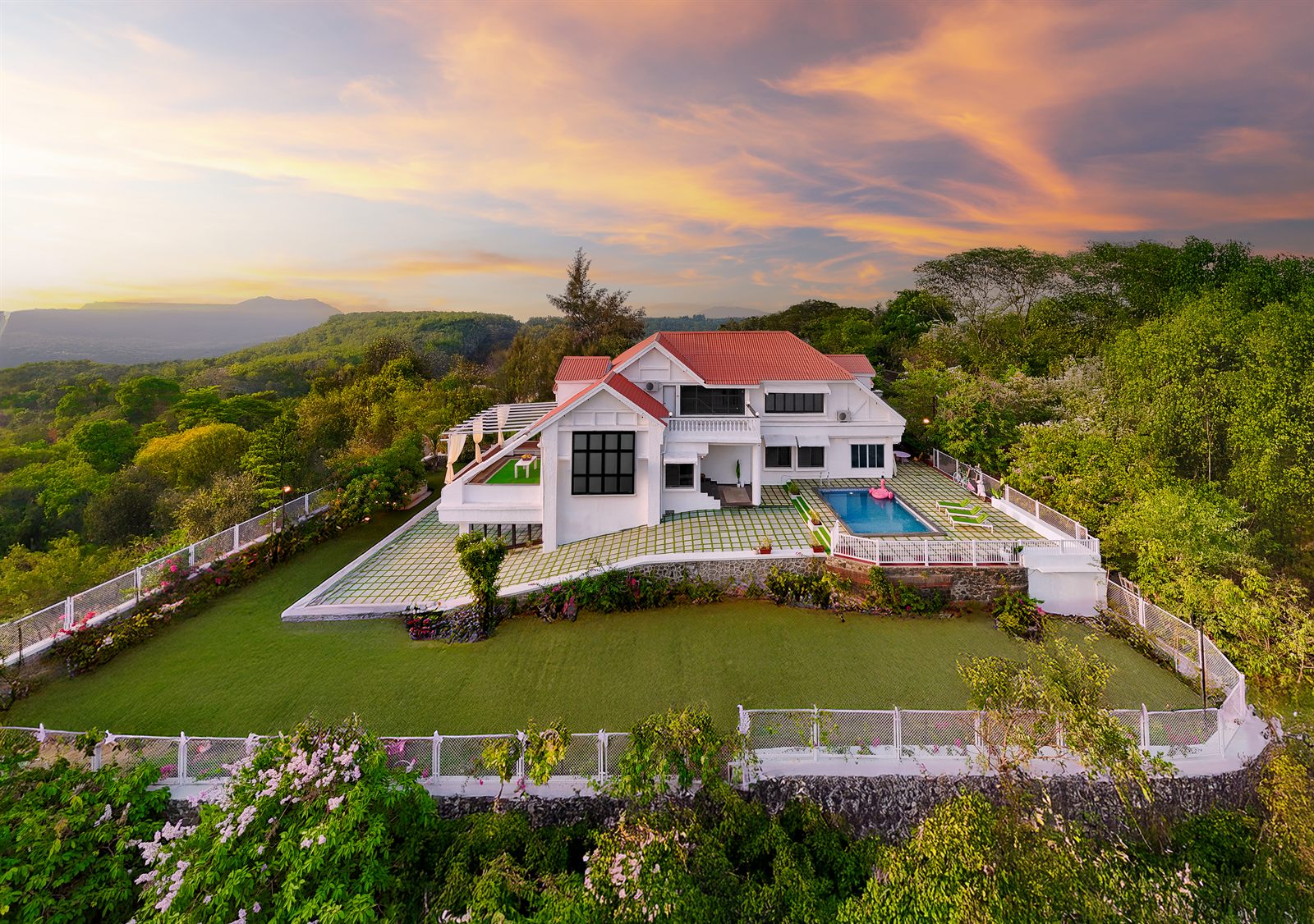 A hilltop EkoStay villa with a private pool and lawn overlooking a valley at sunset